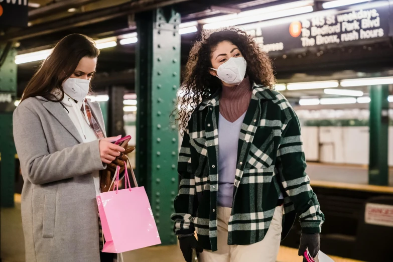 a couple of women standing next to each other on a subway platform, trending on pexels, happening, masked doctors, giving gifts to people, nyc, pink