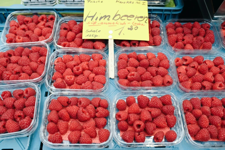 a bunch of plastic containers filled with raspberries, a photo, by Tom Wänerstrand, pexels, stood in a supermarket, handwritten, ham, with a whitish