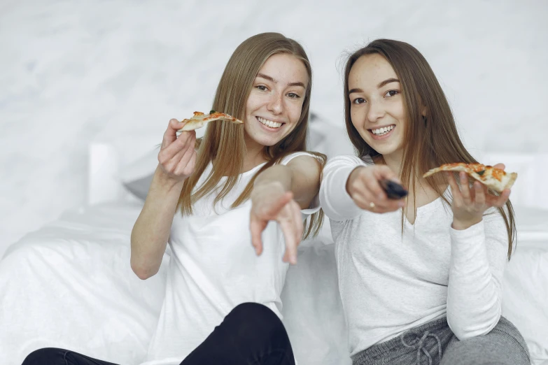 two women sitting on a bed eating pizza, trending on pexels, realism, white bg, teenagers, background image, tv commercial