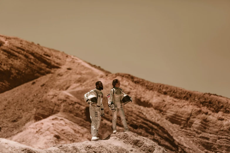 a couple of people standing on top of a mountain, a colorized photo, by Lee Loughridge, pexels contest winner, mars mission, highly detailed diorama, wear spacesuits, sepia photography