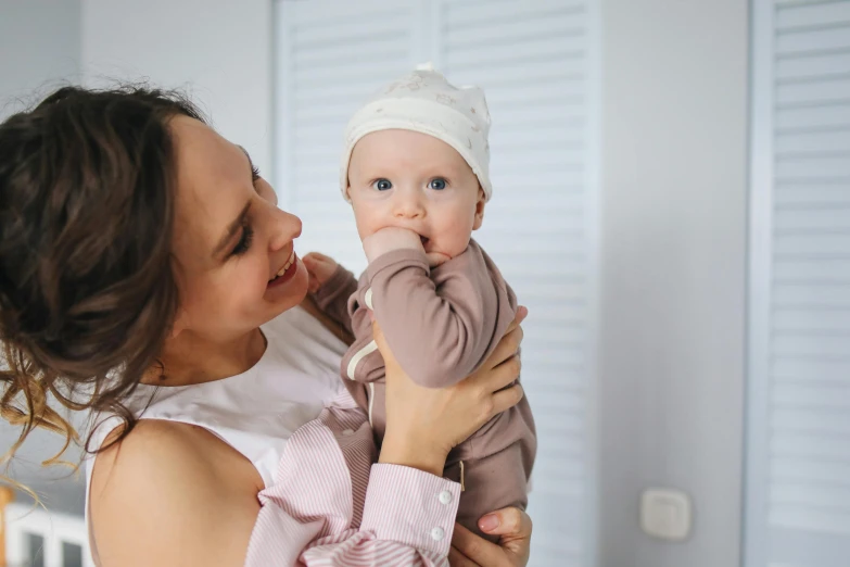 a woman holding a baby in her arms, pexels contest winner, avatar image, manuka, brunette, thumbnail