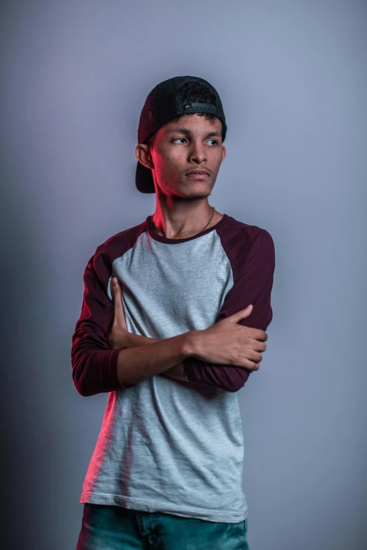 a young man standing with his arms crossed, a character portrait, inspired by Rudy Siswanto, pexels contest winner, with rap cap on head, studio lit, non binary model, aged 13