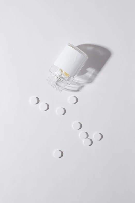 a bottle filled with white pills on top of a white surface, by Évariste Vital Luminais, unsplash, antipodeans, high - angle view, white muzzle and underside, floating pieces, miniature product photo