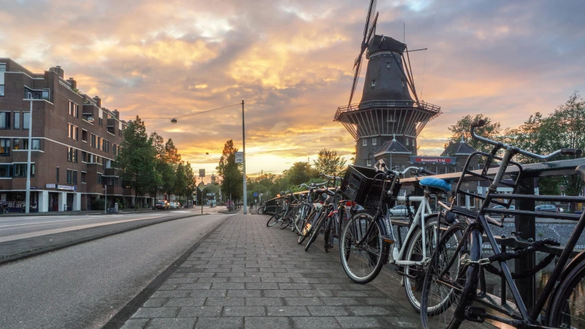 a row of bicycles parked on the side of a road, by Jan Tengnagel, pexels contest winner, happening, dutch windmill gundam, vista of a city at sunset, 🚿🗝📝