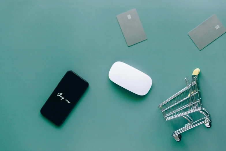 a computer mouse sitting on top of a table next to a shopping cart, a picture, by Jang Seung-eop, unsplash, minimalism, silicone cover, samsung smartthings, white pearlescent, a green