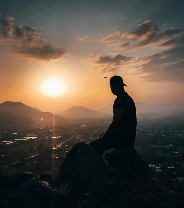 a man sitting on top of a mountain at sunset, by Sebastian Spreng, pexels contest winner, profile pic, today\'s featured photograph 4k, above city, low detailed