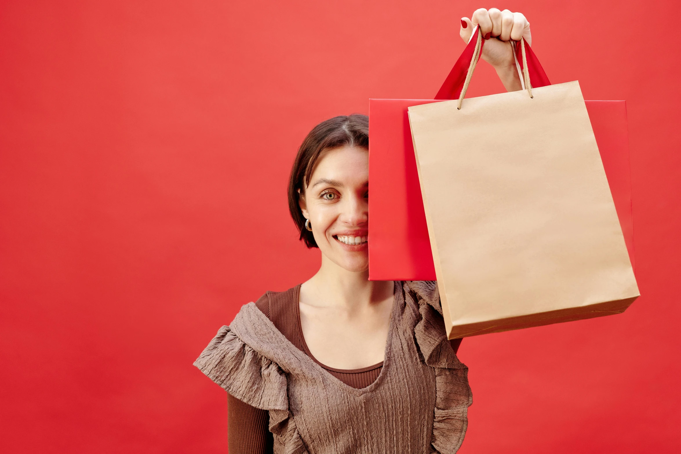 a woman holding two shopping bags in front of her face, pexels contest winner, renaissance, in red background, avatar image, brown paper, smiling woman