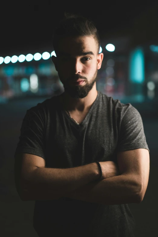 a man standing in the dark with his arms crossed, by Robbie Trevino, discord profile picture, looking confident, in an urban setting, background