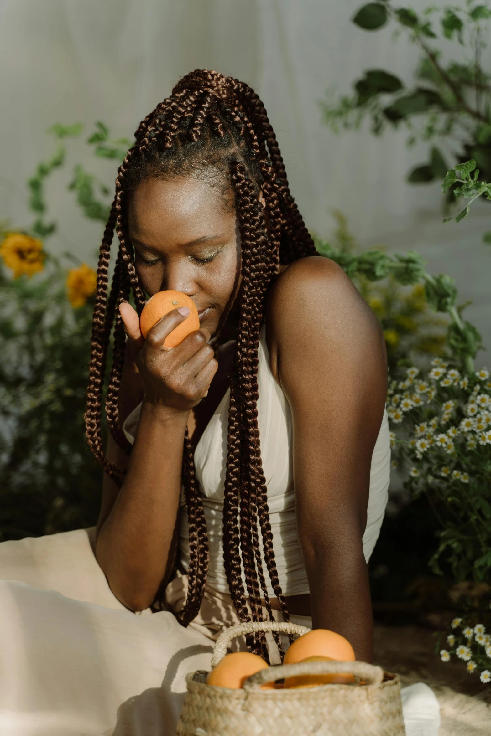 a woman sitting on the ground eating an orange, by Dulah Marie Evans, pexels contest winner, long black braids, profile pic, gardening, sitting on a mocha-colored table