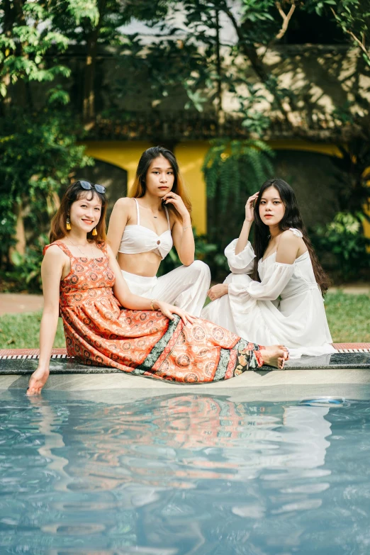 a group of women sitting next to a swimming pool, a picture, unsplash, renaissance, in style of lam manh, portrait pose, three, wearing beautiful clothes