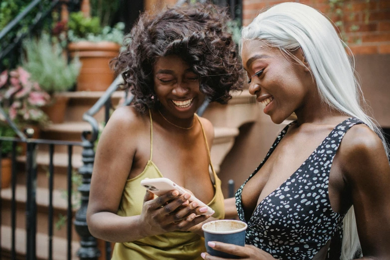 a couple of women standing next to each other, trending on pexels, happening, phone, brown skinned, playful smirk, high quality product image”