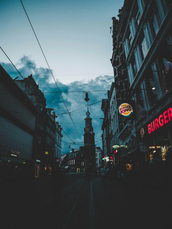 a street filled with lots of traffic next to tall buildings, by Christen Dalsgaard, pexels contest winner, dark university aesthetic, late summer evening, neon lights above shops, street scene with water tower