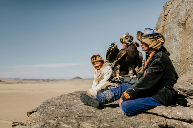 a group of people sitting on top of a large rock, a portrait, by Dietmar Damerau, pexels contest winner, hurufiyya, eagle feather, mongol, avatar image