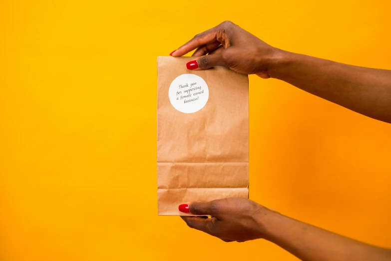 a person holding a brown paper bag with a sticker on it, award - winning crisp details, view from the back, recipe, product shot