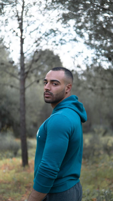 a man standing in the woods with a frisbee, pexels contest winner, les nabis, in a dark teal polo shirt, wearing a hoody, very fit and extremely muscular, profile image