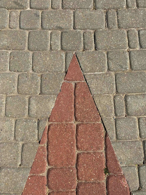 a triangle made out of bricks on a sidewalk, an album cover, inspired by Joel Shapiro, pareidolia, award - winning photo ”, concrete )