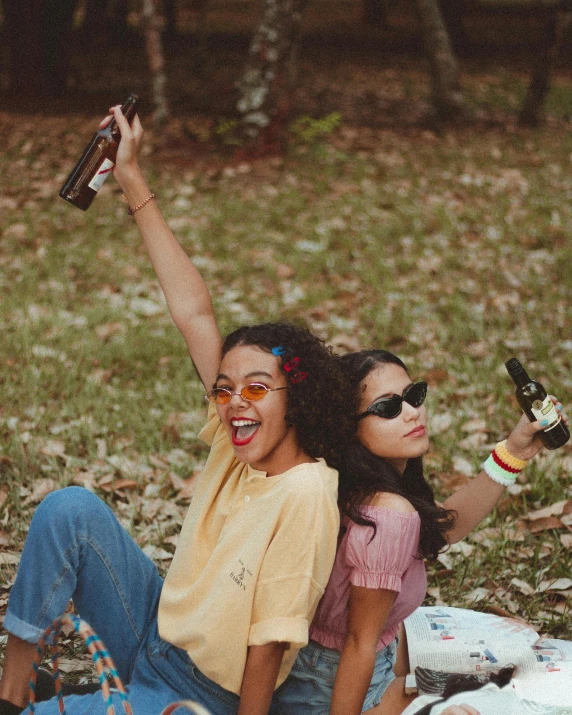 a couple of women sitting on top of a blanket, a polaroid photo, trending on pexels, happening, holding beer bottles, triumphant pose, an olive skinned, pictured from the shoulders up