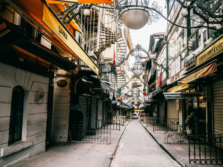 a narrow street lined with shops next to tall buildings, inspired by Elsa Bleda, pexels contest winner, art nouveau, fallout style istanbul, wrought iron architecture, gif, where a large