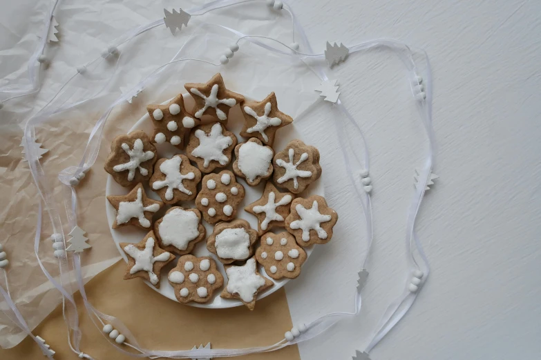 a plate that has some cookies on it, by Sylvia Wishart, unsplash, folk art, white ribbon, emitting light ornaments, white ceramic shapes, close-up product photo