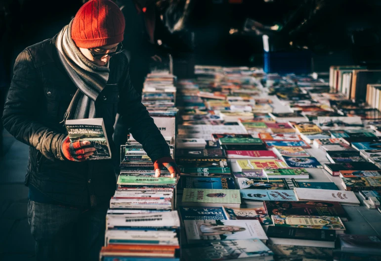 a man standing in front of a table full of books, pexels contest winner, happening, street market, avatar image, reading, medium close-up shot