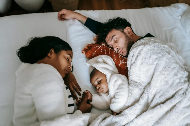 a man and woman laying in bed with a baby, pexels contest winner, varying ethnicities, sleeping beauty, winter, 1 2 9 7