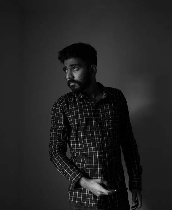 a man standing in a black and white photo, by Ismail Acar, jayison devadas, poorly lit, wearing a flannel shirt, monochrome:-2