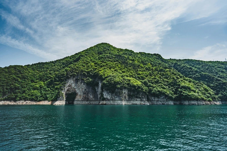 a mountain in the middle of a body of water, inspired by Tadao Ando, pexels contest winner, mingei, overgrown stone cave, chiba prefecture, chalk cliffs above, today\'s featured photograph 4k