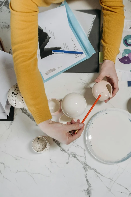 a woman is painting eggs on a table, inspired by artist, trending on pexels, process art, white vase, architect, holding a planet, porcelain