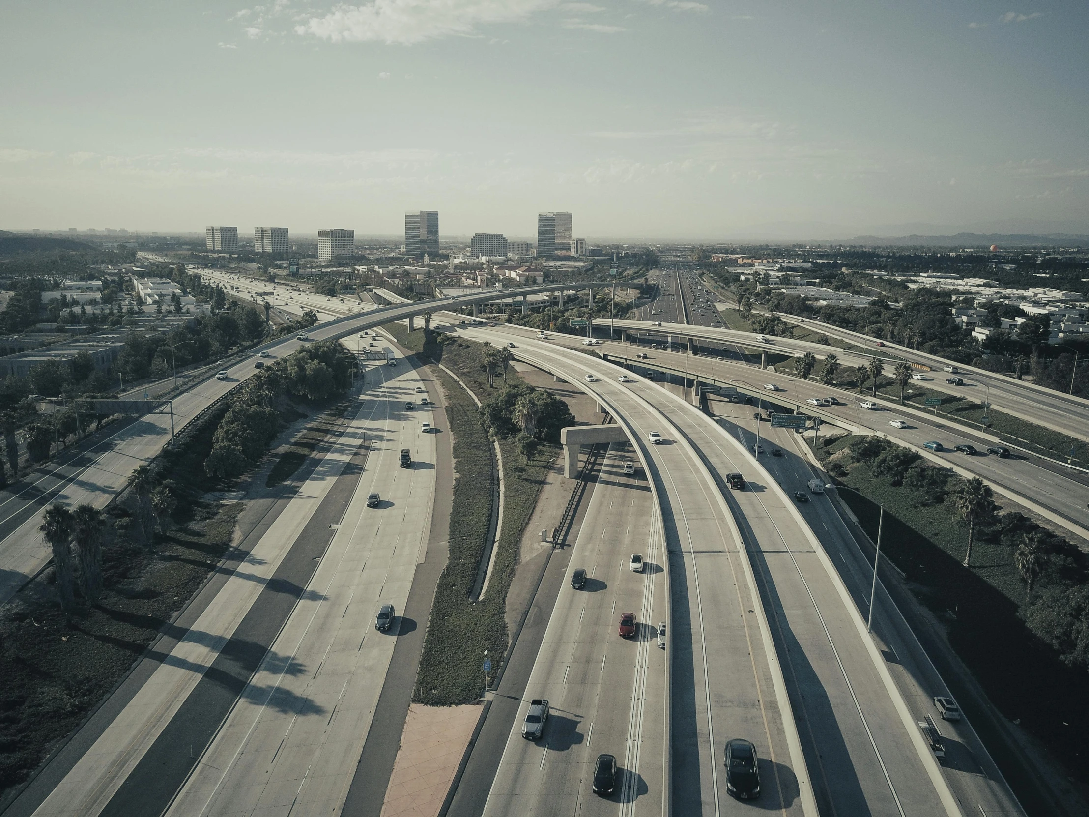 a freeway filled with lots of traffic next to tall buildings, a detailed matte painting, unsplash, hyperrealism, southern california, drone photograpghy, grain”, overpass