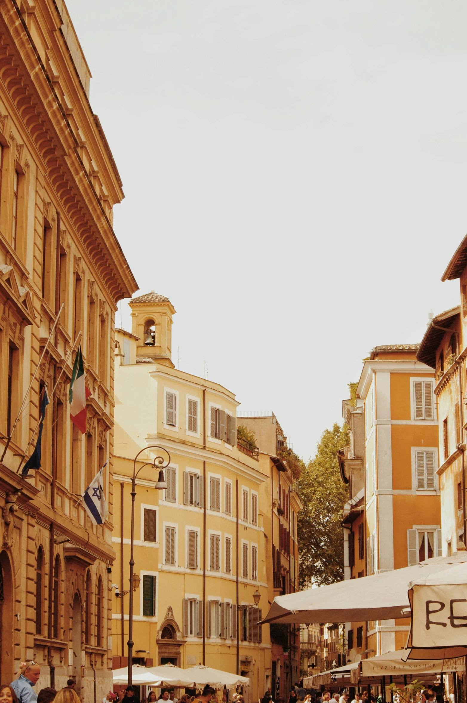 a group of people walking down a street next to tall buildings, neoclassicism, rome, yellow awning, houses, atmospheric photograph