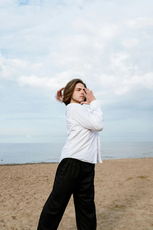 a woman standing on a beach talking on a cell phone, an album cover, by Nina Hamnett, unsplash, portrait androgynous girl, white wrinkled shirt, man standing in defensive pose, frank dillane