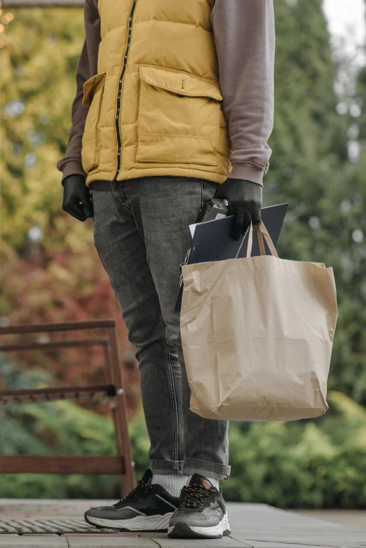 a man standing on a sidewalk holding a bag, brown paper, wearing gloves, on high-quality paper, at home