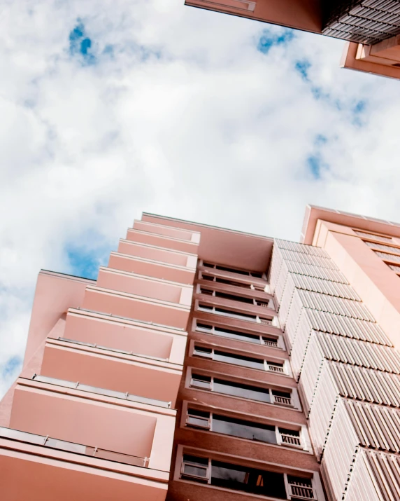 a tall building with a blue sky in the background, inspired by Ricardo Bofill, unsplash, brown and pink color scheme, manly, low quality photo, nice slight overcast weather