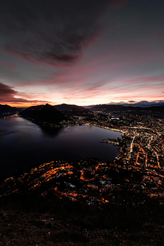 a view of a city from the top of a mountain, by Johannes Voss, pexels contest winner, renaissance, lakeside, evening lights, new zealand, screensaver