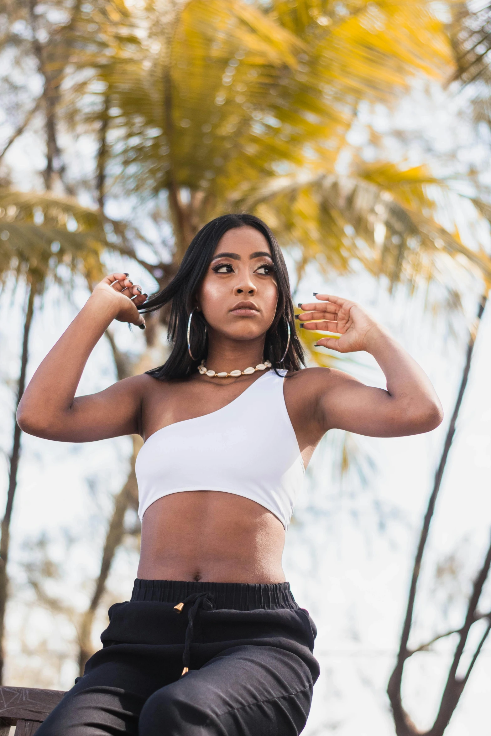 a woman sitting on top of a wooden bench, by Robbie Trevino, croptop, indian girl with brown skin, in a beachfront environment, in front of white back drop