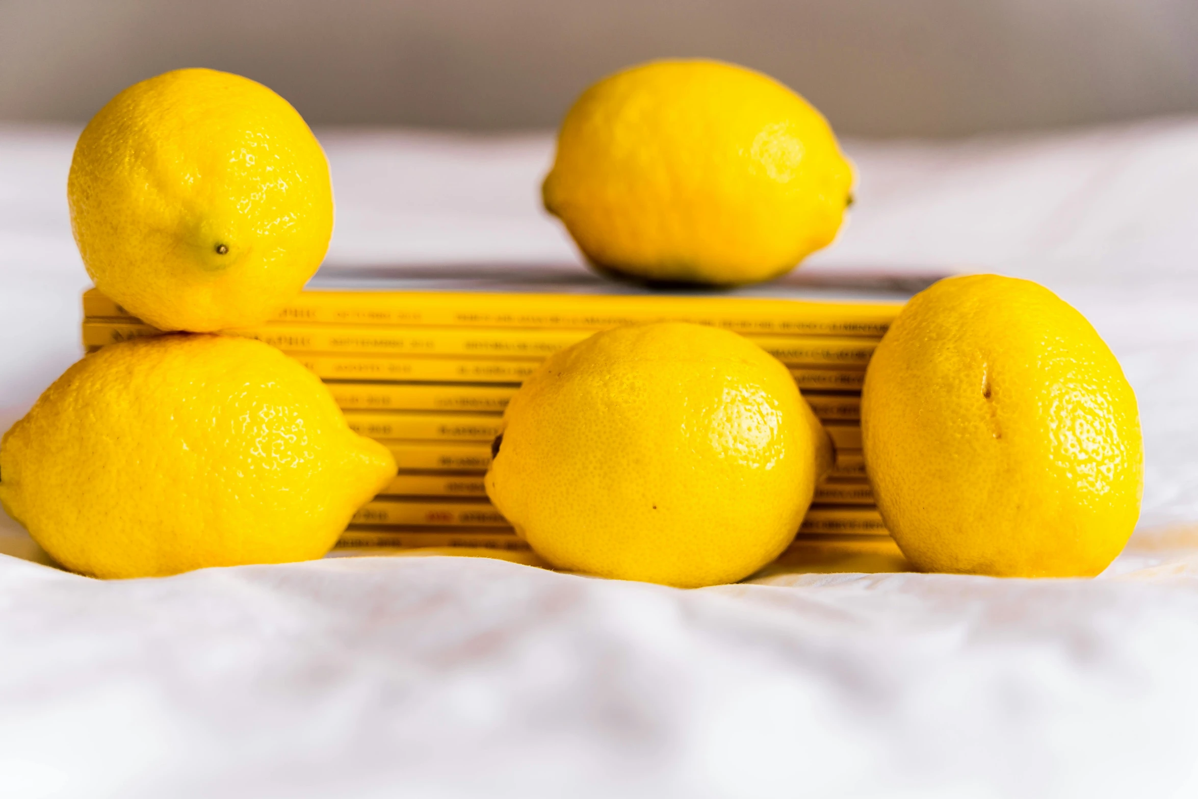 a stack of lemons sitting on top of a bed, a still life, pexels, 6 pack, long, creating a soft, flattened