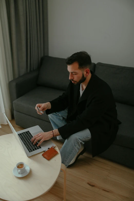 a man sitting on the floor using a laptop, by Adam Marczyński, pexels contest winner, wearing business casual dress, sofa, demna gvasalia, sitting on man's fingertip