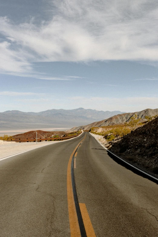 a man riding a motorcycle down the middle of a road, by Whitney Sherman, trending on unsplash, death valley, panoramic, high quality photo, usa-sep 20