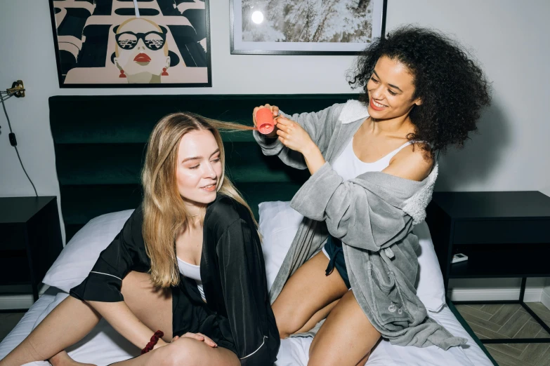 a couple of women sitting on top of a bed, trending on unsplash, styled hair, wearing a robe, bowater charlie and brom gerald, college girls