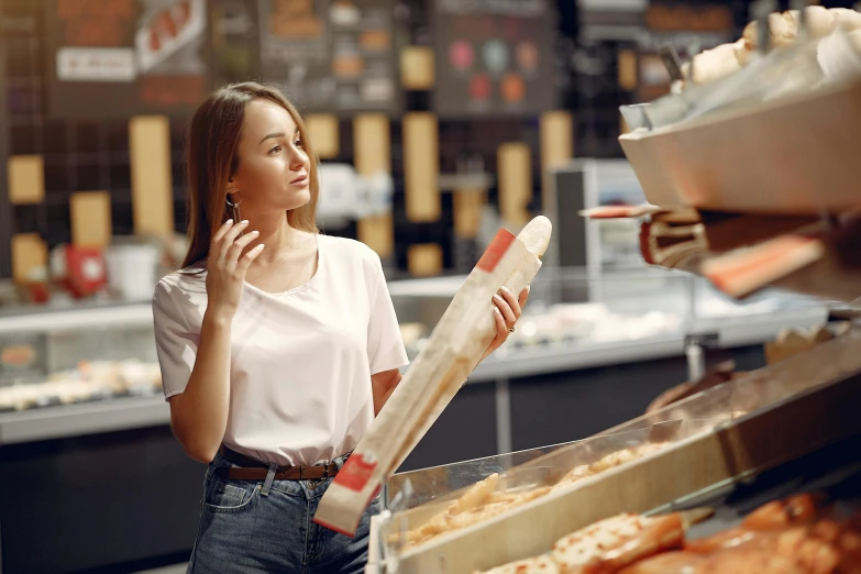 a woman talking on a cell phone in a bakery, by Niko Henrichon, pexels contest winner, hyperrealism, stood in a supermarket, australian, holding a baguette, profile image