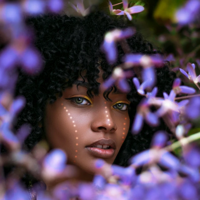 a close up of a woman's face surrounded by purple flowers, pexels contest winner, afrofuturism, brown skinned, cute woman, photo of a beautiful, markings on her face