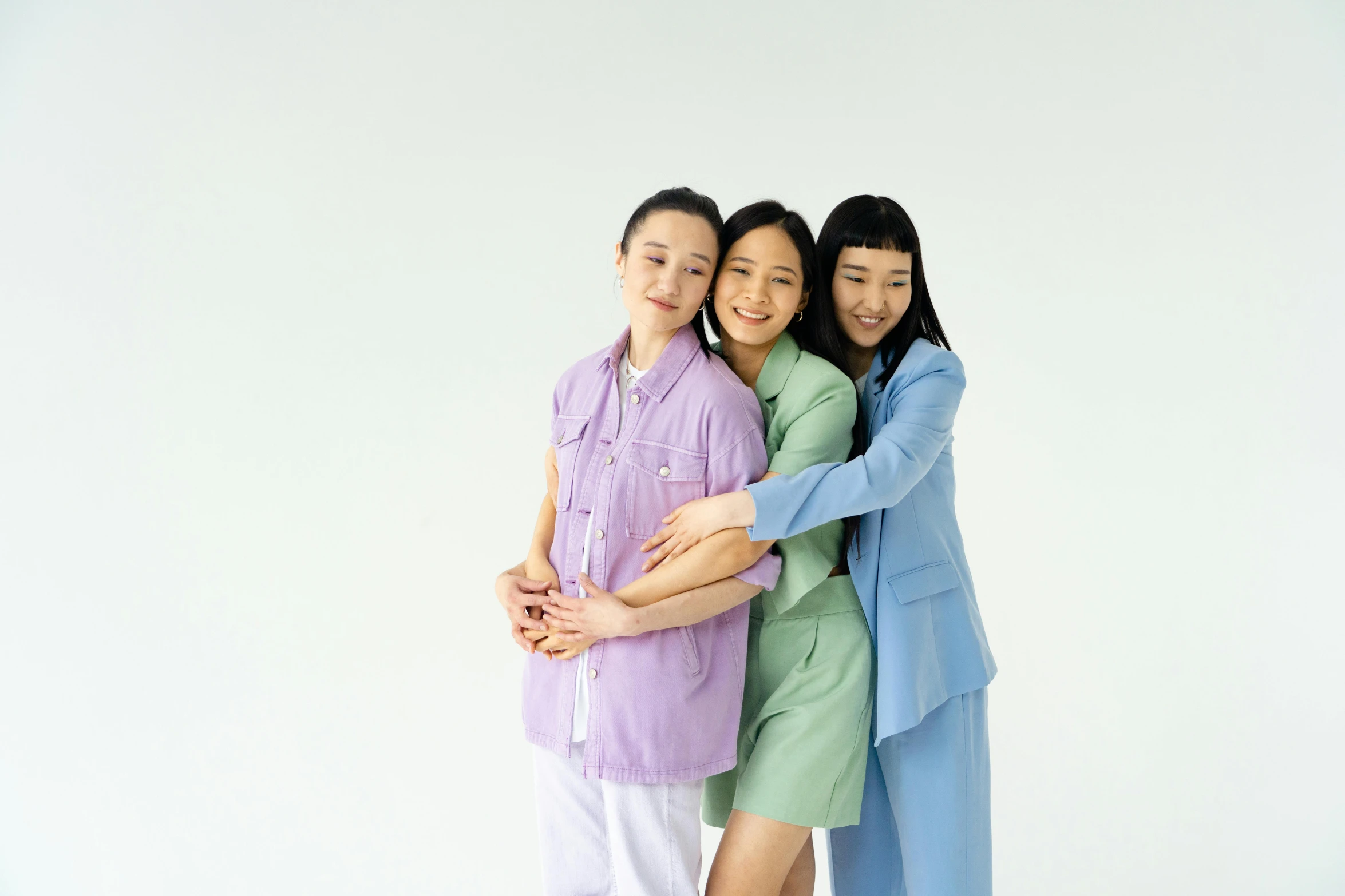 a couple of women standing next to each other, inspired by Zhang Xiaogang, pexels, dau-al-set, sleepwear, three women, hugging each other, colorful uniforms