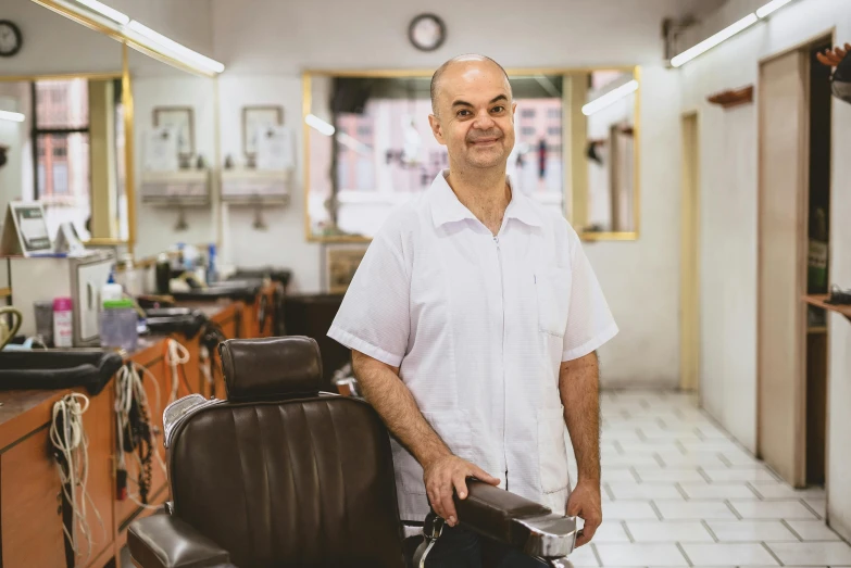 a man standing next to a chair in a barber shop, profile image