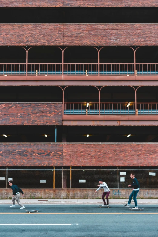 a group of people riding skateboards down a street, unsplash, brutalism, brick building, coventry city centre, panoramic shot, brown