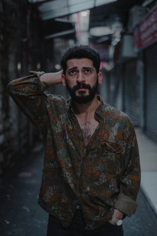 a man with a beard standing in an alleyway, an album cover, by Elsa Bleda, pexels contest winner, middle eastern skin, annoyed, patterned clothing, ( ( theatrical ) )