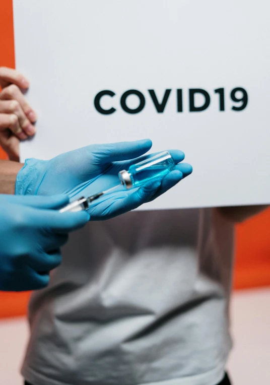 a person in blue gloves holding a sign, an album cover, by Matt Cavotta, shutterstock, blood collection vials, covid, implants, instagram post