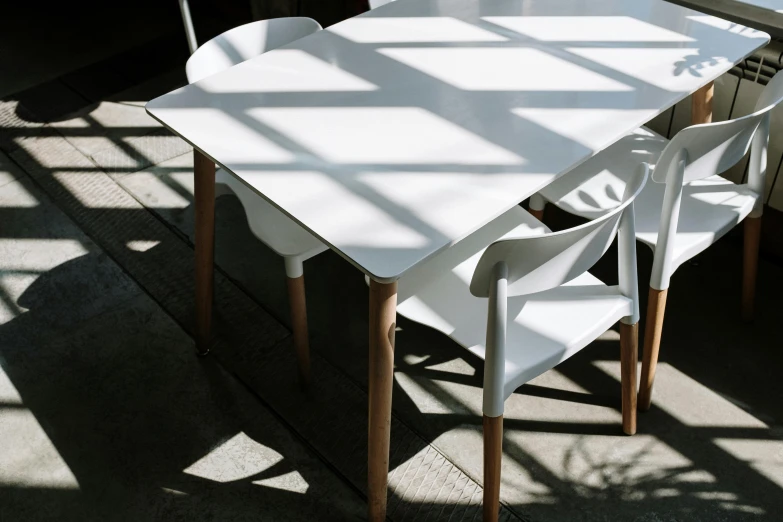 a white table and some chairs in a room, inspired by Eero Snellman, unsplash contest winner, dappled afternoon sunlight, white plastic, strong shadow, eating outside