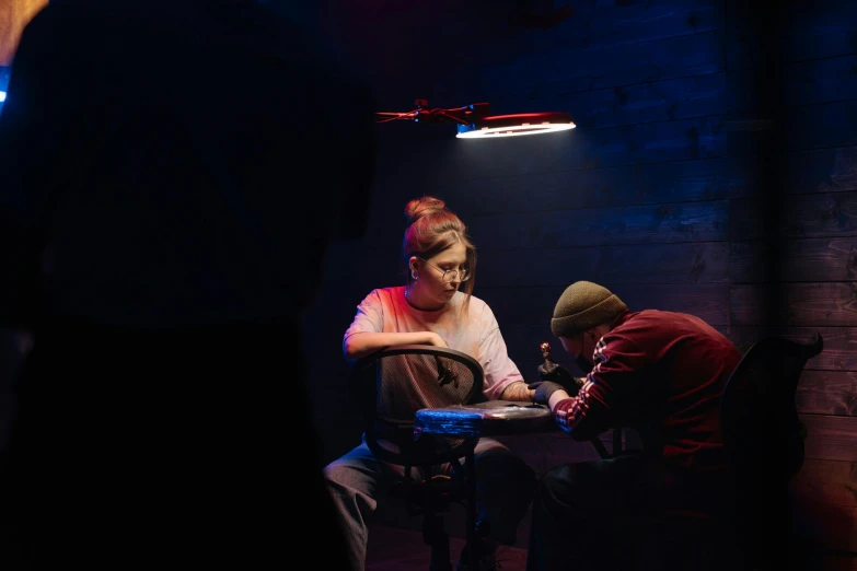two people sitting at a table in a dark room, cinematatic lighting, playing games, high drama, birdseye view