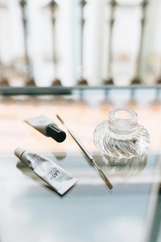 a pair of scissors sitting on top of a glass table, skincare, curated collection, complimentary eyeliner, grey