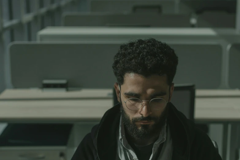 a man sitting at a desk using a laptop computer, inspired by Youssef Howayek, pexels contest winner, serial art, still from movie, looking serious, working in a call center, cinestill eastmancolor